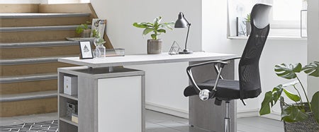 A sunny office featuring the ULLITS computer desk with storage from JYSK Canada, complemented by the BILLUM black mesh back office chair. Faux plants along complete the setup, providing a stylish and functional workspace.